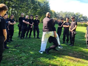 Zdjęcie przedstawia uczniów klasy policyjnych podczas zajęć z policjantem.