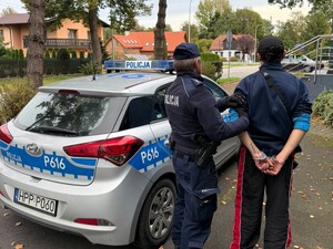 Zdjęcie przedstawia umundurowanego policjanta z zatrzymanym mężczyzną.